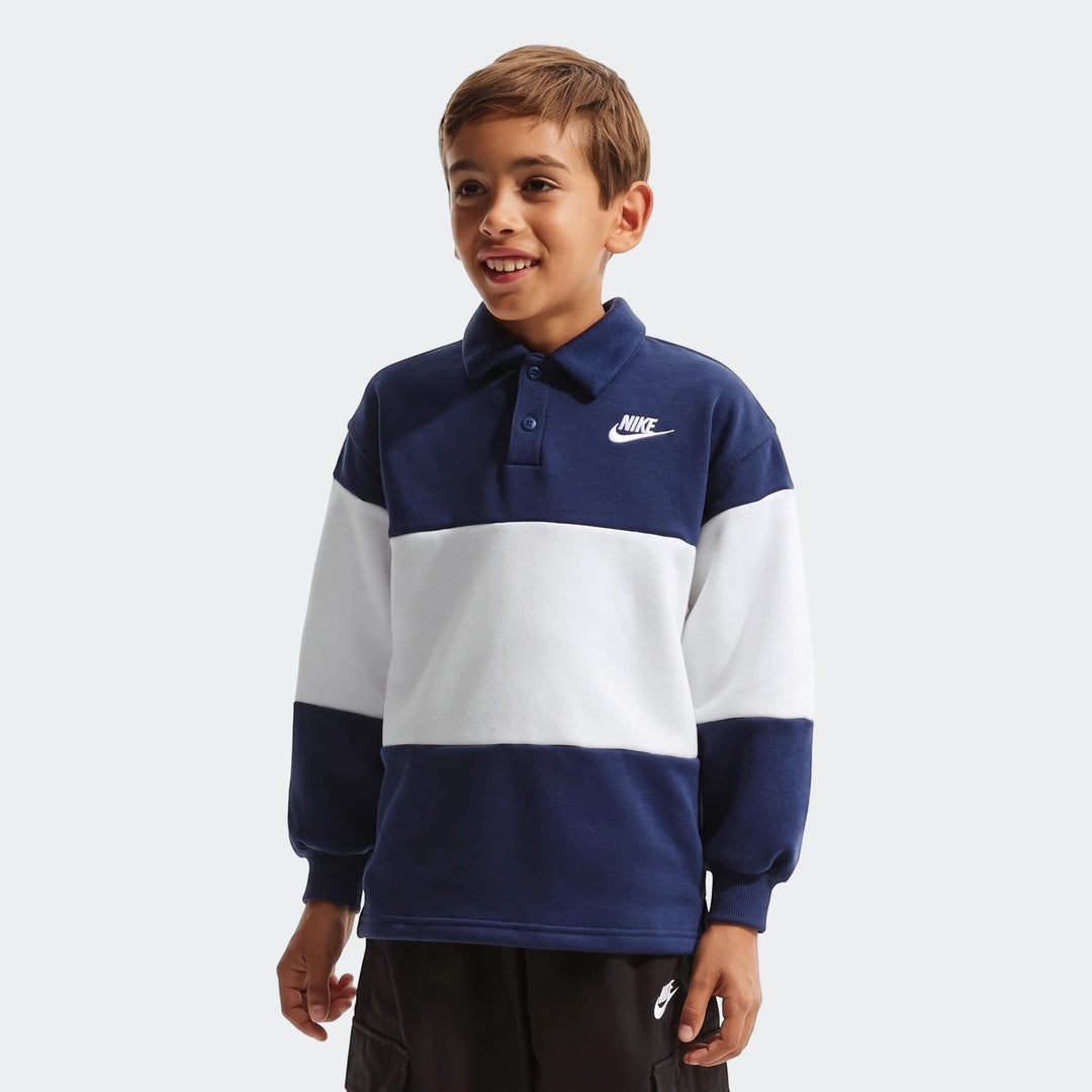 Young boy wearing a Nike K Nsw Club Rugby long-sleeve blue and white striped shirt with a collar and black shorts.