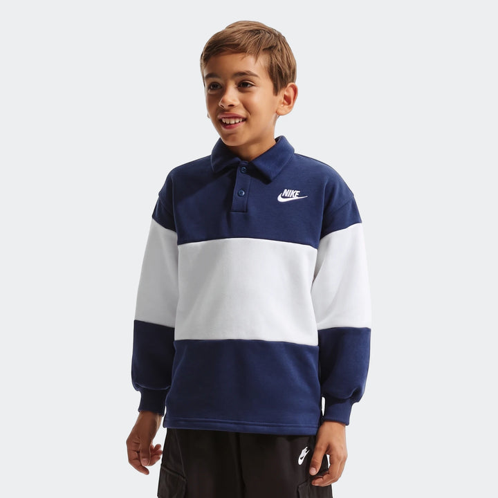 Young boy wearing a Nike K Nsw Club Rugby long-sleeve blue and white striped shirt with a collar and black shorts.