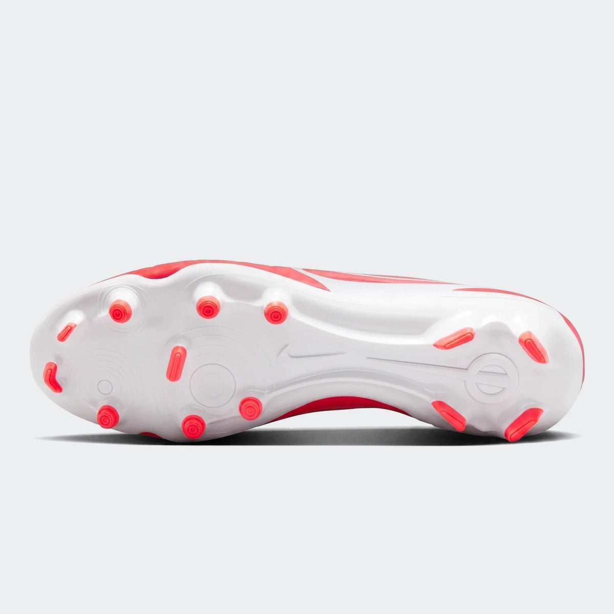 Bottom view of a red and white Nike Legend 10 Club FG/MG football boot, showcasing the white sole and red studs.