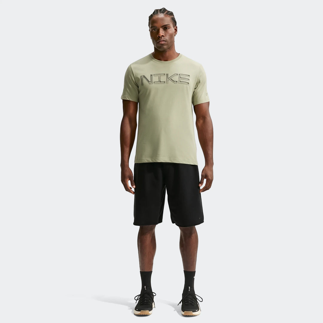 Full body shot of a man wearing a light green Nike Dri-Fit training t-shirt and black shorts, standing on a white background.