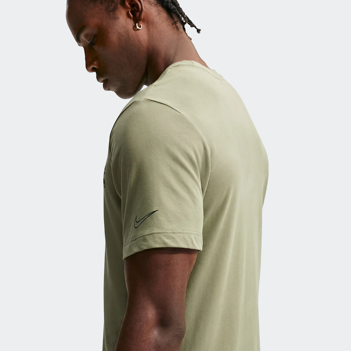 Close-up side profile of a man wearing a light olive green Nike Men's Dri-Fit Training T-Shirt with braided hair.