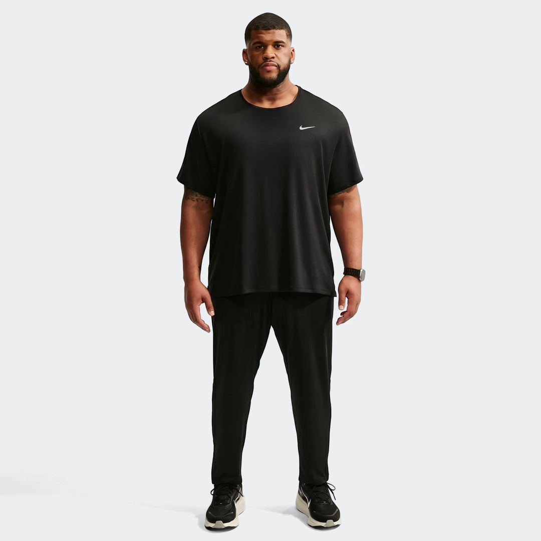 A man wearing black Nike Dri-Fit knit running pants, a black short-sleeve t-shirt with a white Nike logo, and black and