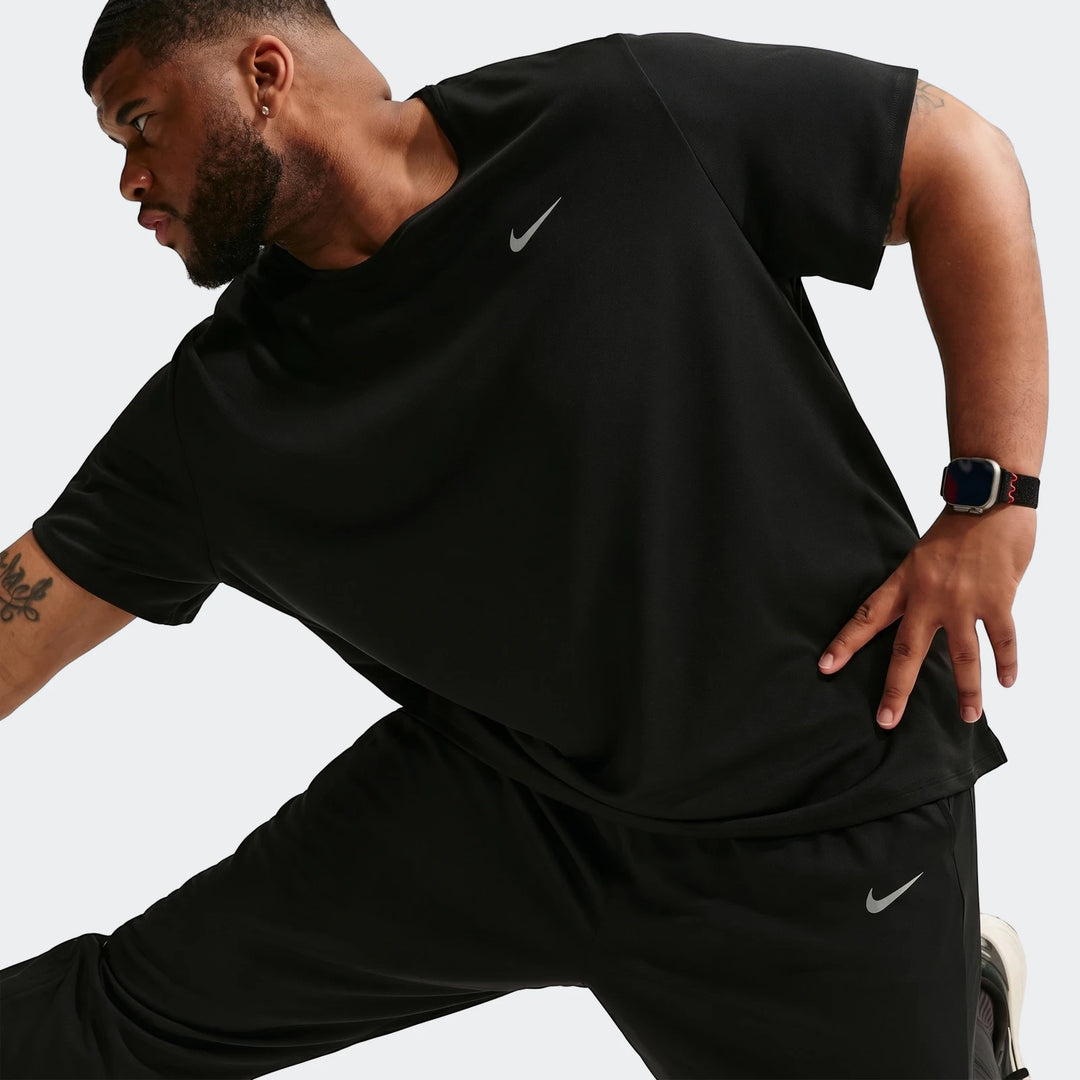 Black Nike Miler Dri-Fit knit running pants and t-shirt on a male model, captured in a dynamic pose for athletic wear.