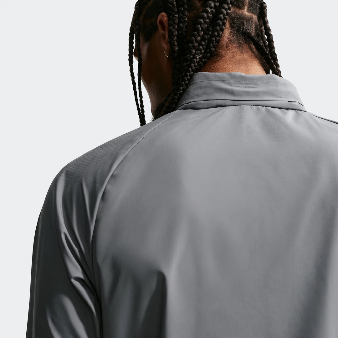 Back view of a man wearing a grey Nike Miler Repel UV Protection Running Jacket, showing braided hair and a gold earring.