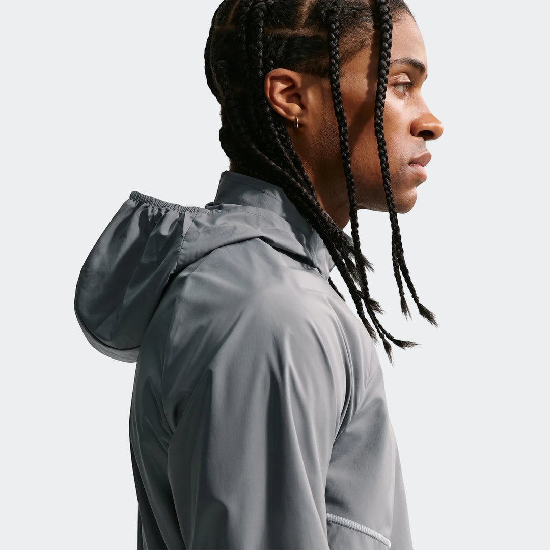 Profile view of a man wearing a grey Nike Miler Repel UV Protection Running Jacket, featuring braided hair and a gold hoop