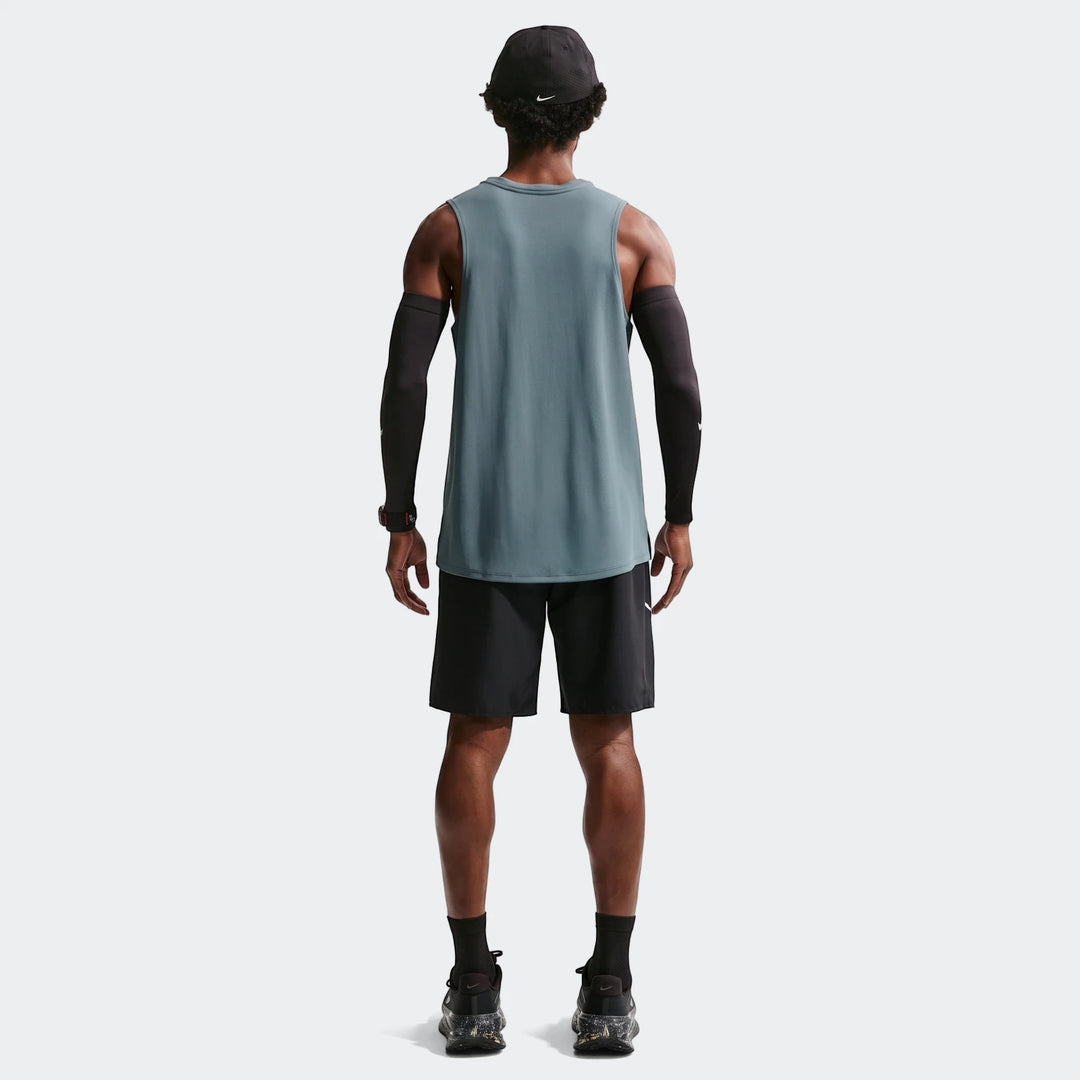 Rear view of a man wearing Nike Miler Men'S Dri-Fit 9" Unlined Running Shorts, a teal tank top, black arm sleeves, and a