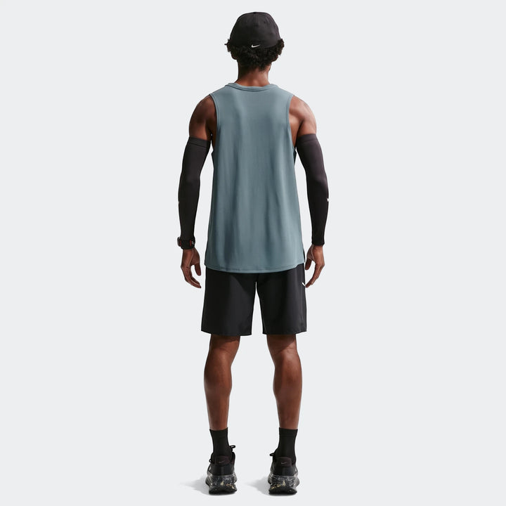 Rear view of a man wearing Nike Miler Men'S Dri-Fit 9" Unlined Running Shorts, a teal tank top, black arm sleeves, and a