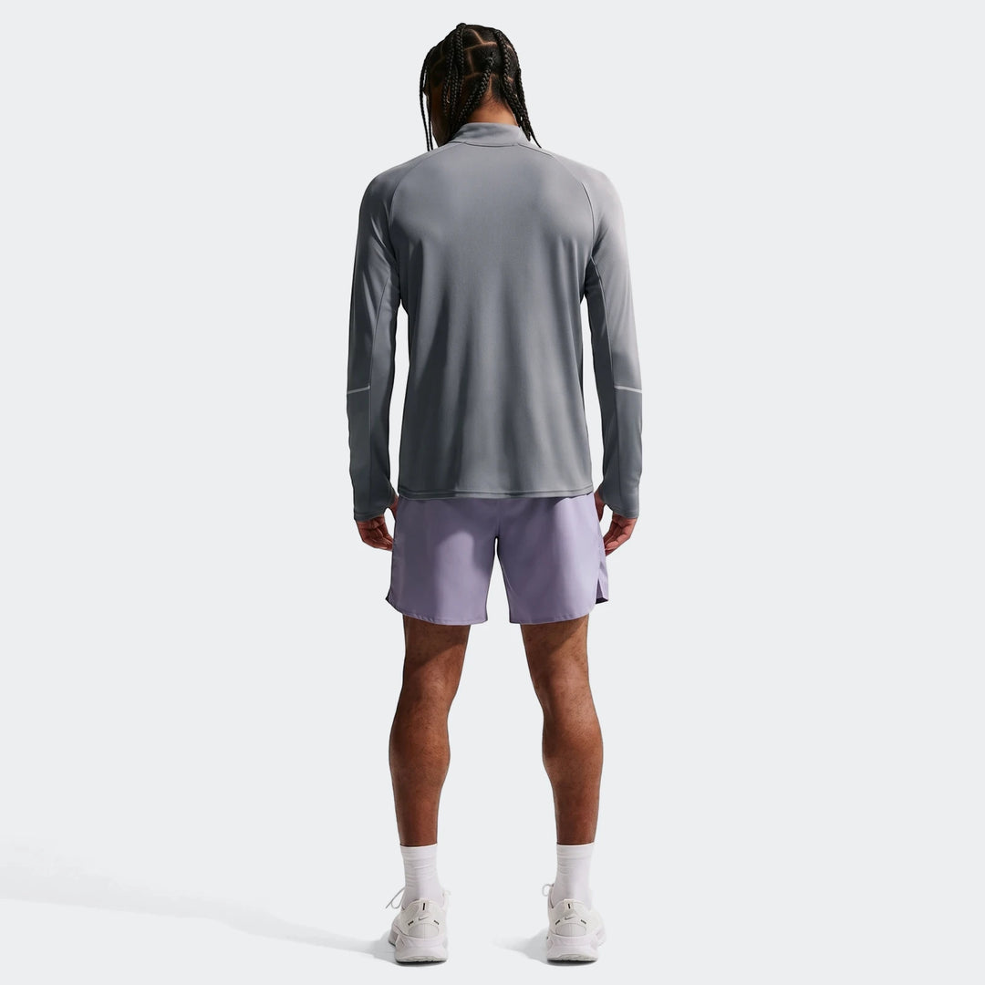 Rear view of a man wearing a Nike Miler grey Dri-Fit 1/2-Zip Running Top and purple athletic shorts.