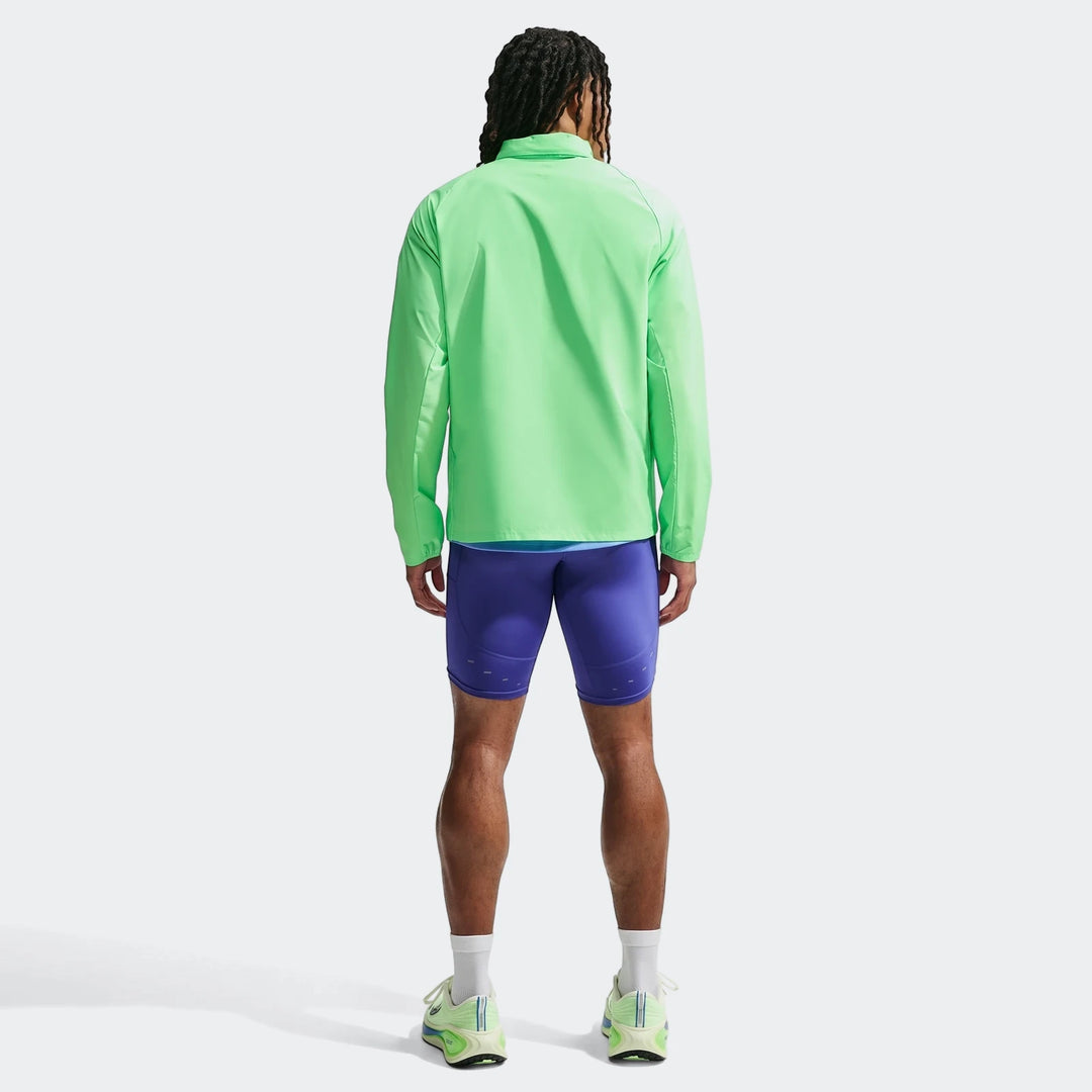 Man from behind wearing a bright green Nike Miler Men's Repel UV Protection Running Jacket and purple shorts.