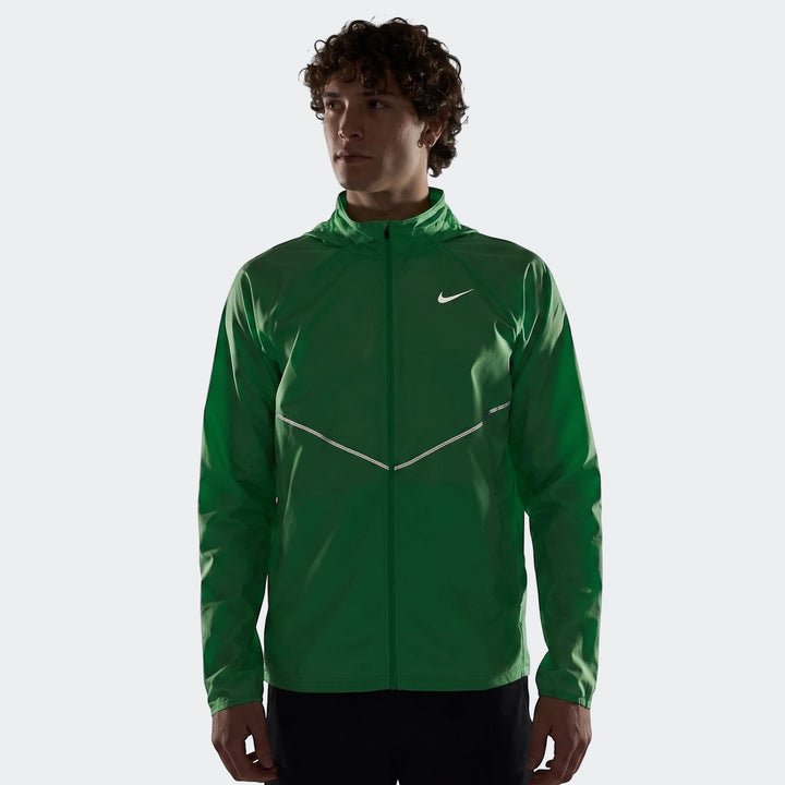 Male model wearing a green Nike Miler Men's Repel UV Protection Running Jacket with reflective details in a studio setting.