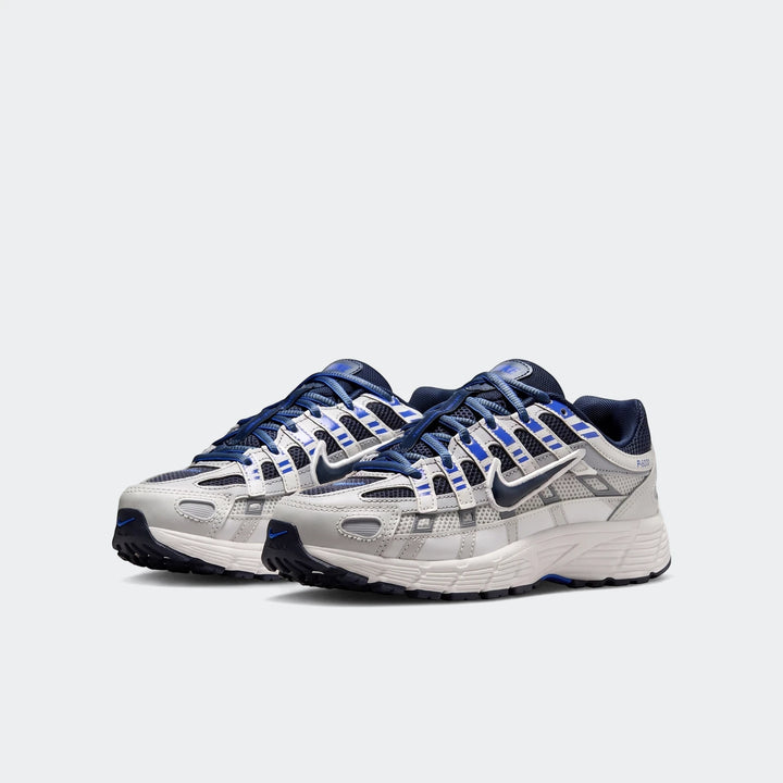 Nike P-6000 Big Kids' Shoes in white, grey, and blue, featuring mesh and leather overlays, shown in a side view.