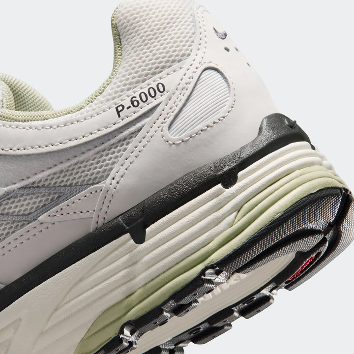 Close-up view of a light grey and black Nike P-6000 men's shoe, focusing on the heel and midfoot details.