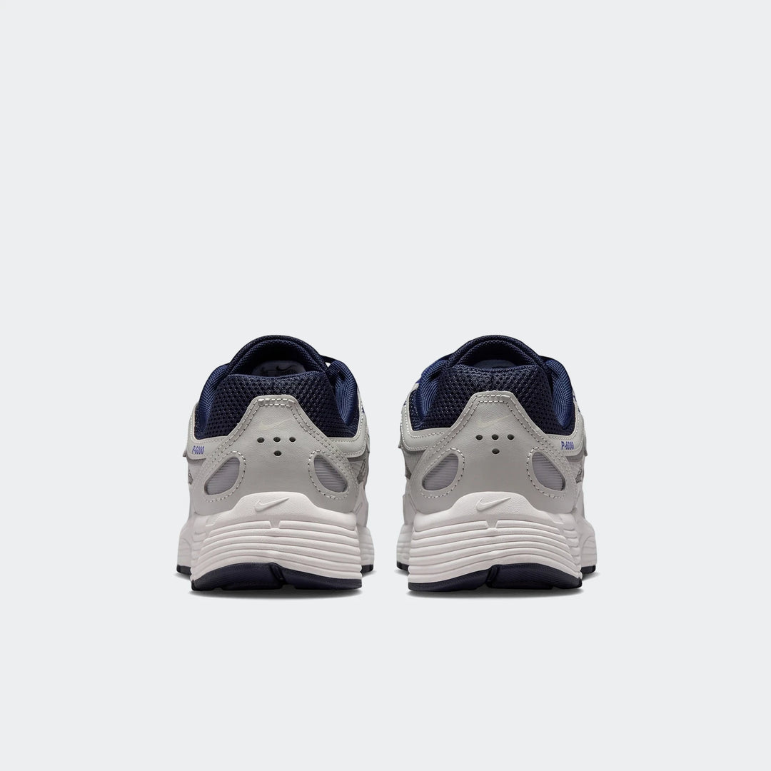 Rear view of two Nike P-6000 Big Kids' Shoes in gray, white, and dark blue, showcasing their design and heel details.