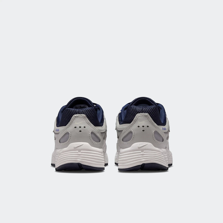 Rear view of two Nike P-6000 Big Kids' Shoes in gray, white, and dark blue, showcasing their design and heel details.