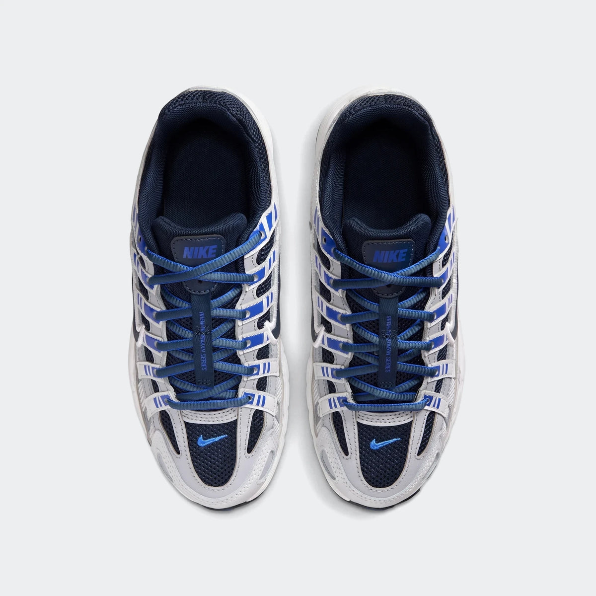 Overhead view of a pair of Nike P-6000 Big Kids' shoes in white, grey, and blue, with blue laces.