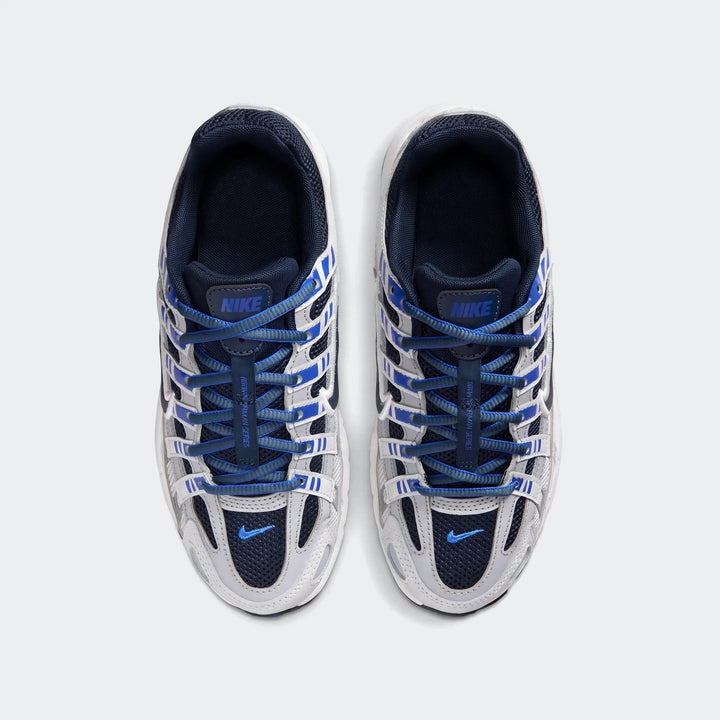 Overhead view of a pair of Nike P-6000 Big Kids' shoes in white, grey, and blue, with blue laces.