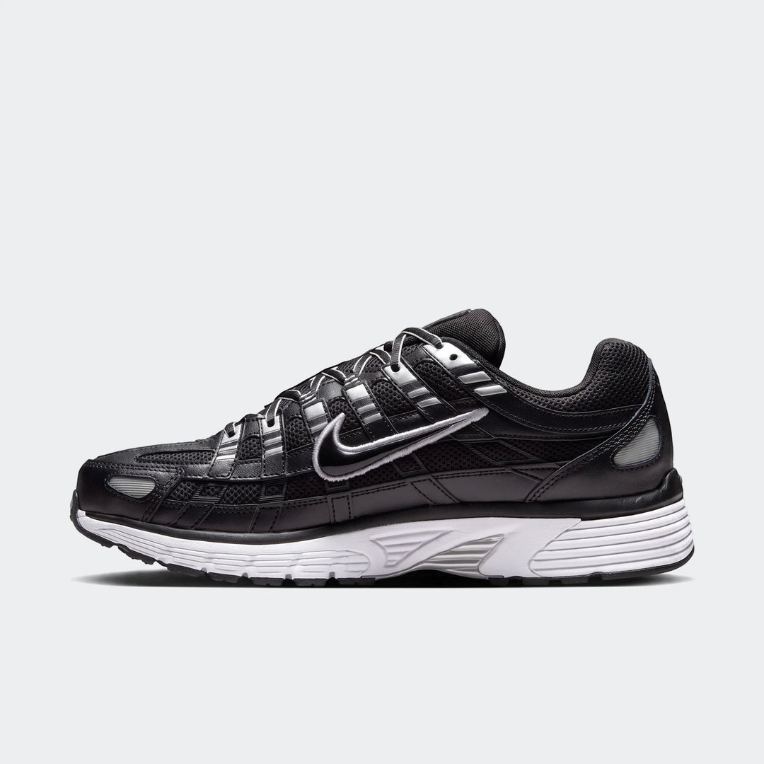 Black and silver Nike P-6000 athletic shoe, featuring mesh and metallic overlays with a white midsole, side view.