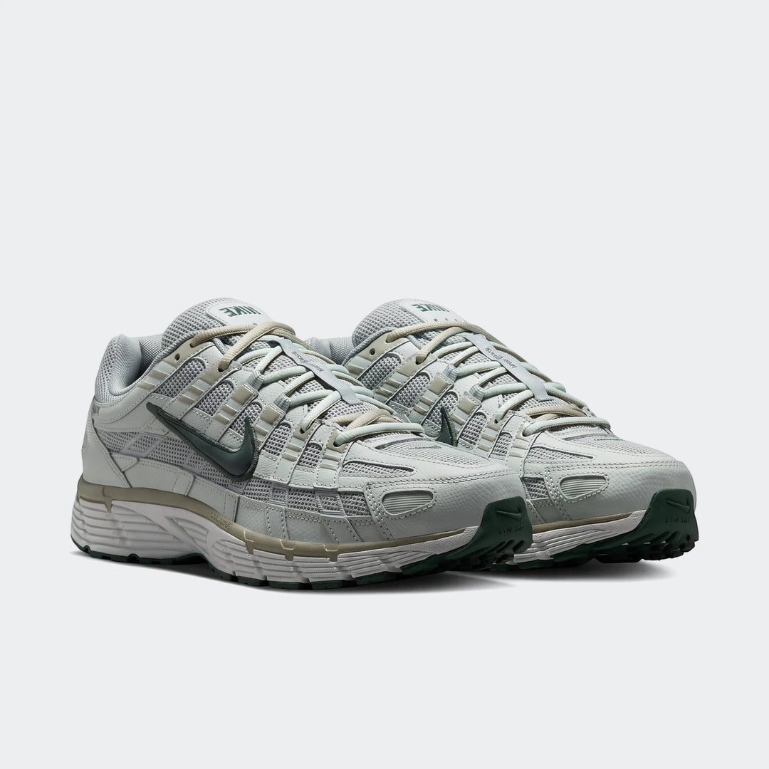 A pair of light grey and dark green Nike P-6000 men's athletic shoes, featuring a mesh and synthetic layered upper,