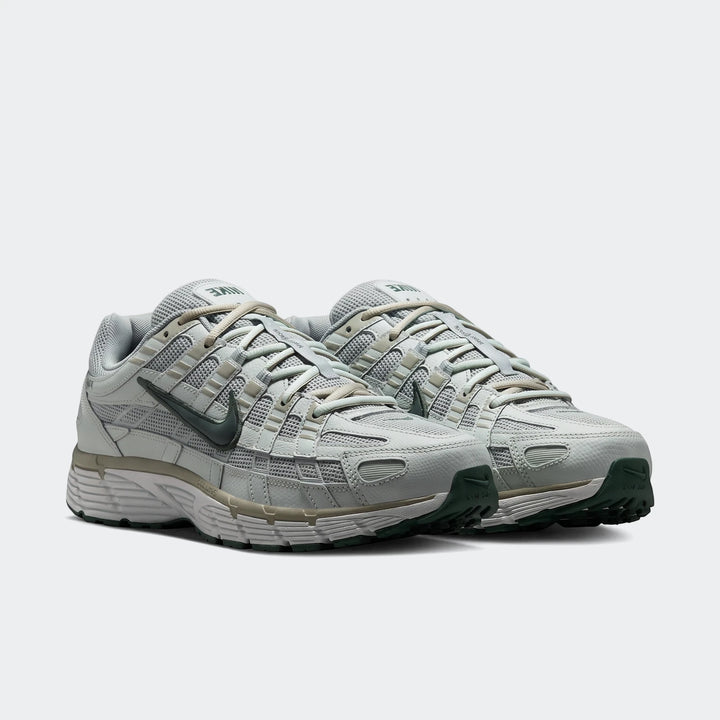 A pair of light grey and dark green Nike P-6000 men's athletic shoes, featuring a mesh and synthetic layered upper,