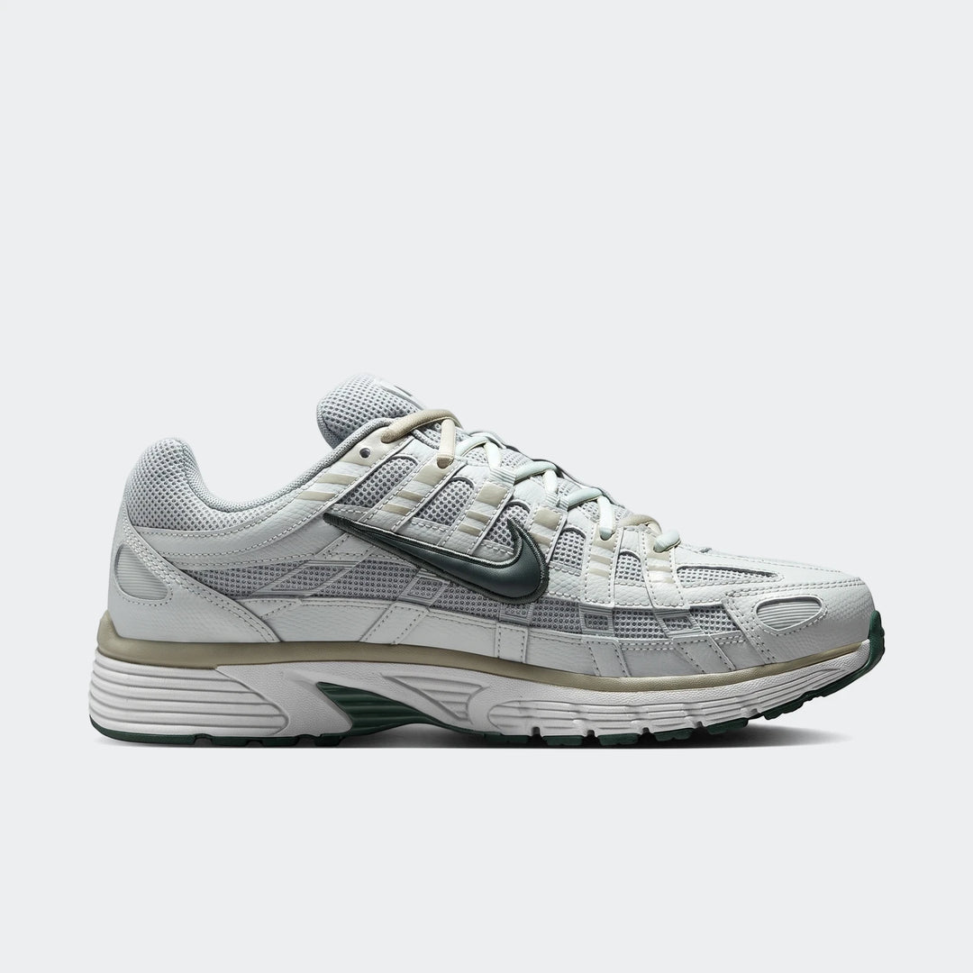 Light grey and dark green Nike P-6000 men's athletic shoe, side view, showcasing its mesh and leather design.