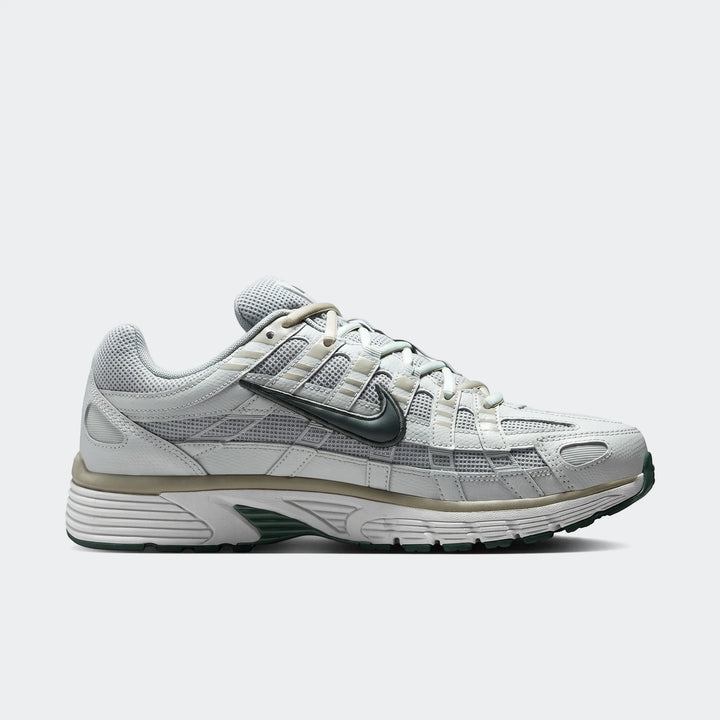Light grey and dark green Nike P-6000 men's athletic shoe, side view, showcasing its mesh and leather design.