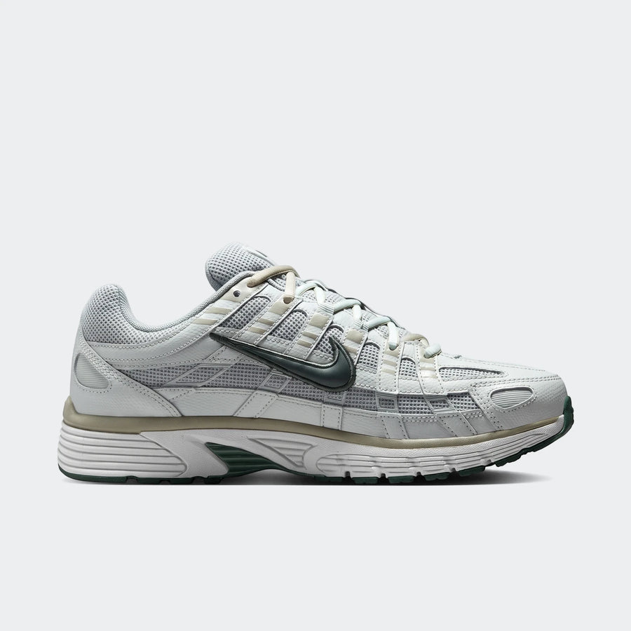 Light grey and dark green Nike P-6000 men's athletic shoe, side view, showcasing its mesh and leather design.