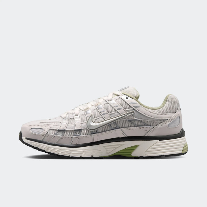 Side view of a Nike P-6000 men's shoe in light grey, white, and metallic silver with green accents.