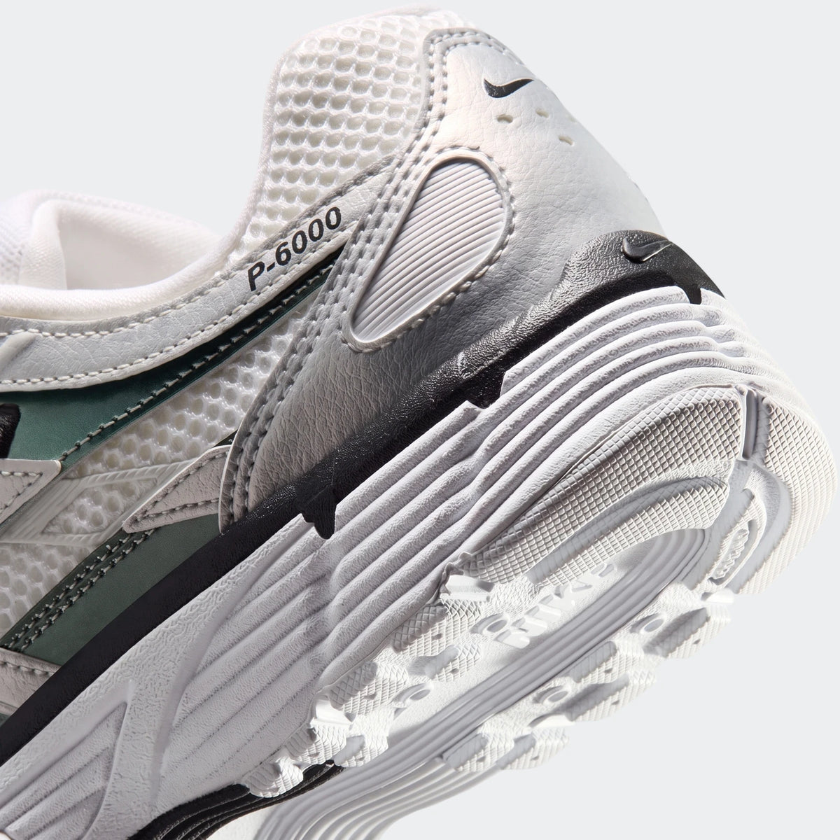 Close-up view of the Nike P-6000 Women's shoes in white, grey, and green, highlighting the heel and sole details.