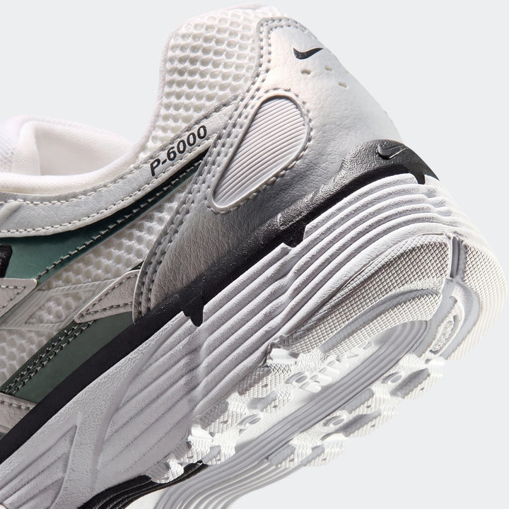 Close-up view of the Nike P-6000 Women's shoes in white, grey, and green, highlighting the heel and sole details.