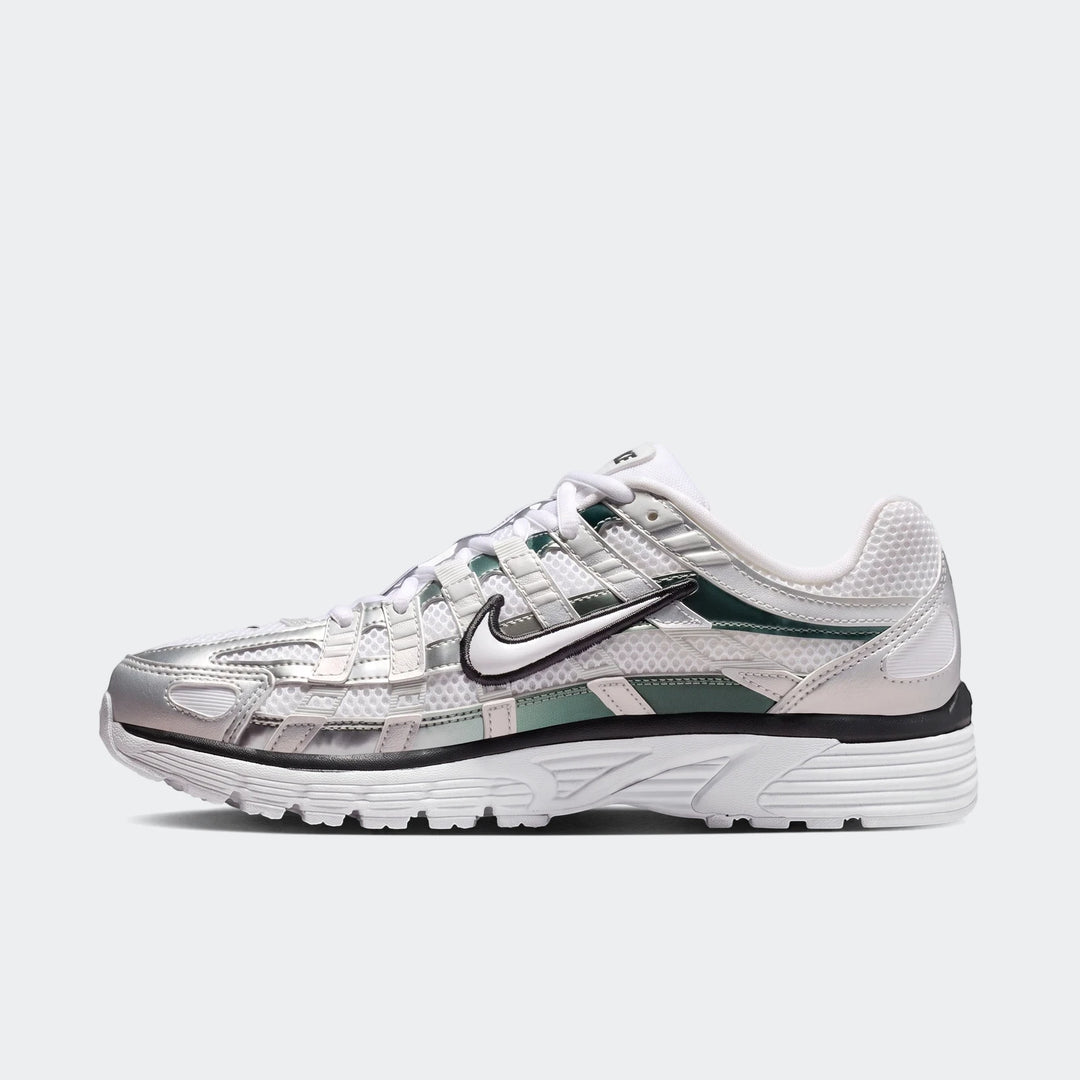 Side view of Nike P-6000 women's shoes featuring white mesh, silver metallic overlays, and green accents. A prominent black