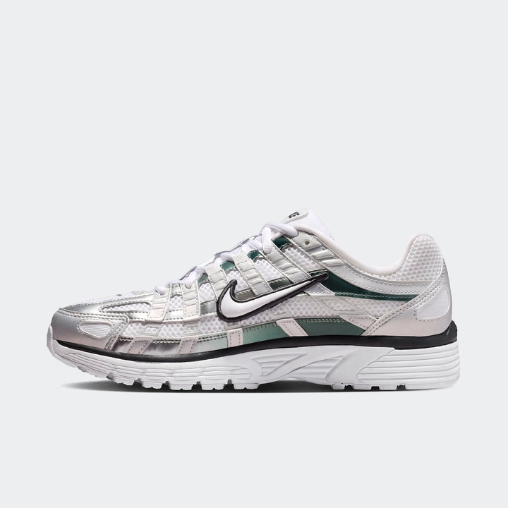 Side view of Nike P-6000 women's shoes featuring white mesh, silver metallic overlays, and green accents. A prominent black