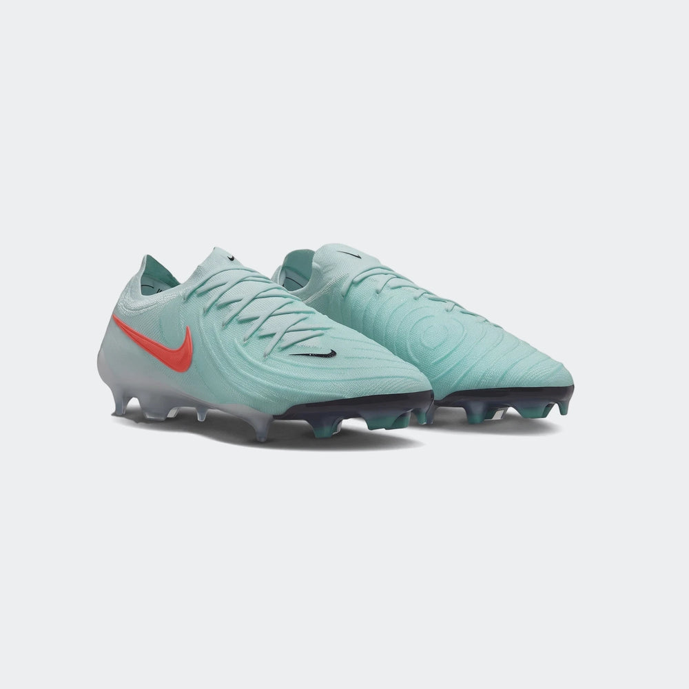 A pair of Nike Phantom Gx 11 Club Fg/Mg Green Boots in teal/mint green with an orange swoosh and black studded soles, ready