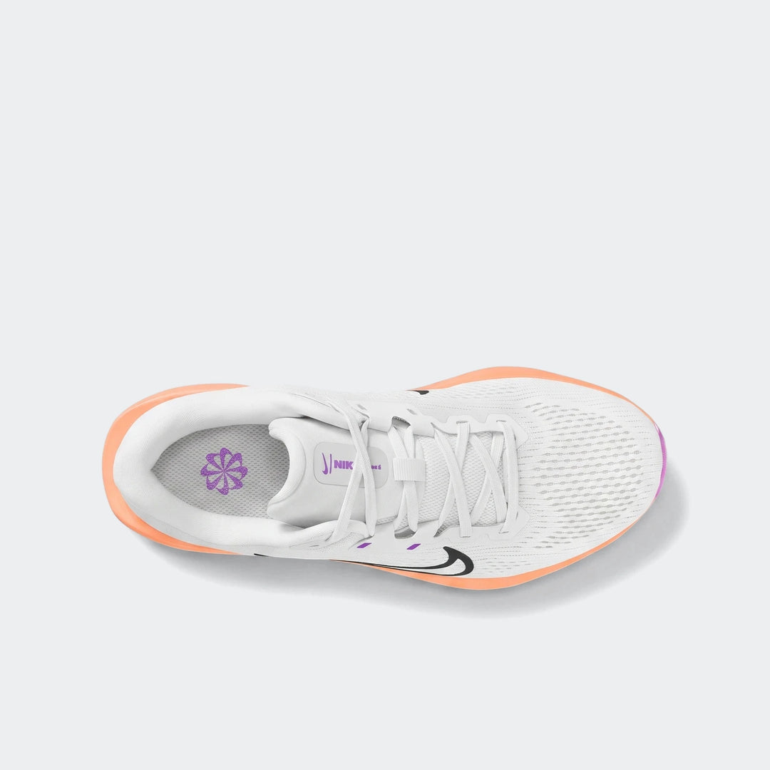 Top-down view of a white Nike Quest 6 running shoe with orange trim and purple accents, showing its mesh upper and signature