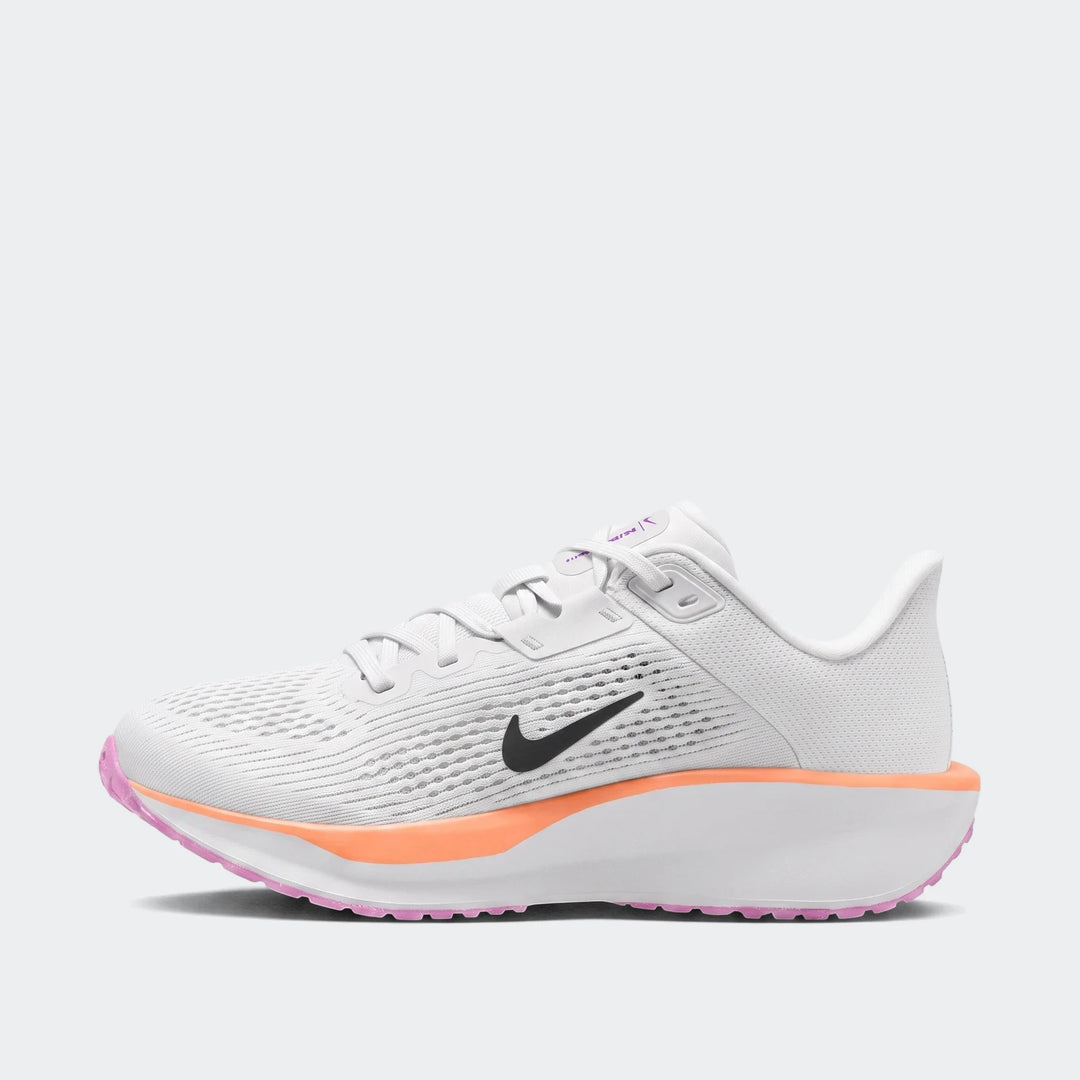 Nike Quest 6 white running sneakers in a side profile view, featuring a black swoosh logo, orange midsole, and pink outsole.