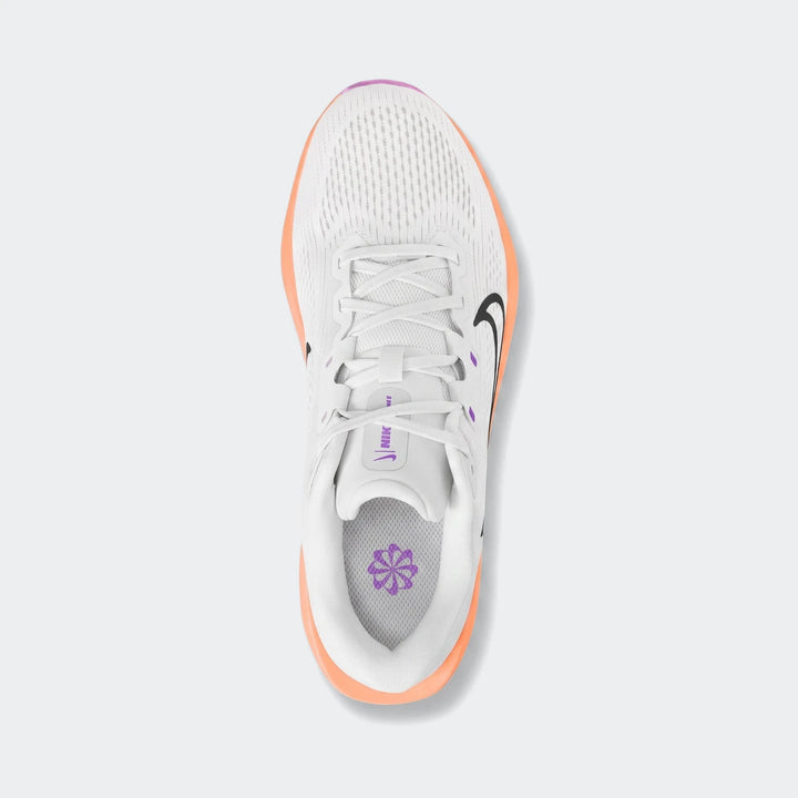 Nike Quest 6 white running sneakers with orange soles and purple accents, viewed from above on a flat background.