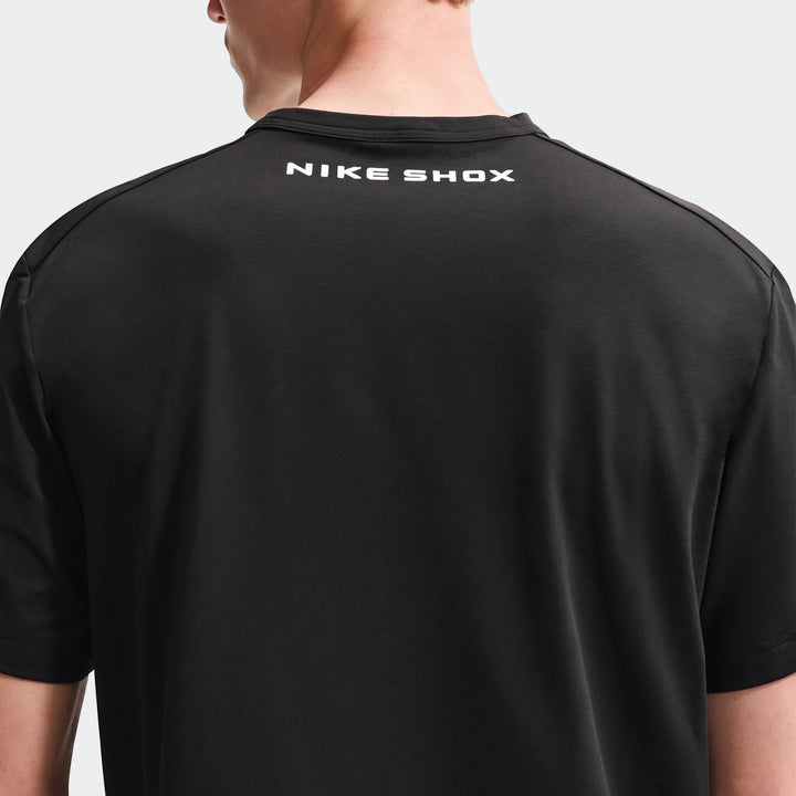 Back view of a male model wearing a black Nike Shox T-Shirt, showcasing the white logo on the back collar. Made from soft,