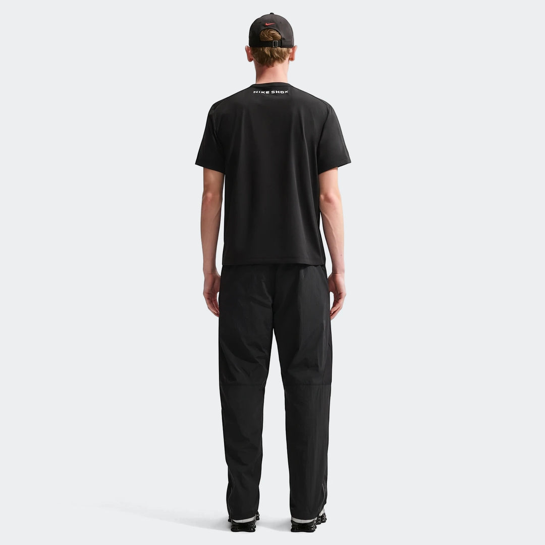 Mens Core Black Nike Shox T-Shirt with black pants and cap, shown from the back on a male model.