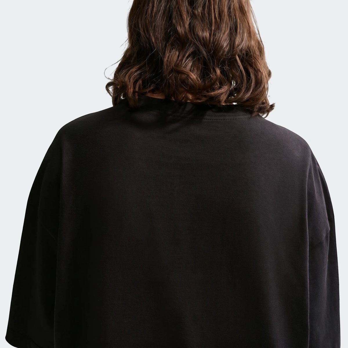 Nike Sportswear Classic black oversized women's t-shirt, styled from the back with a person's wavy brown hair.