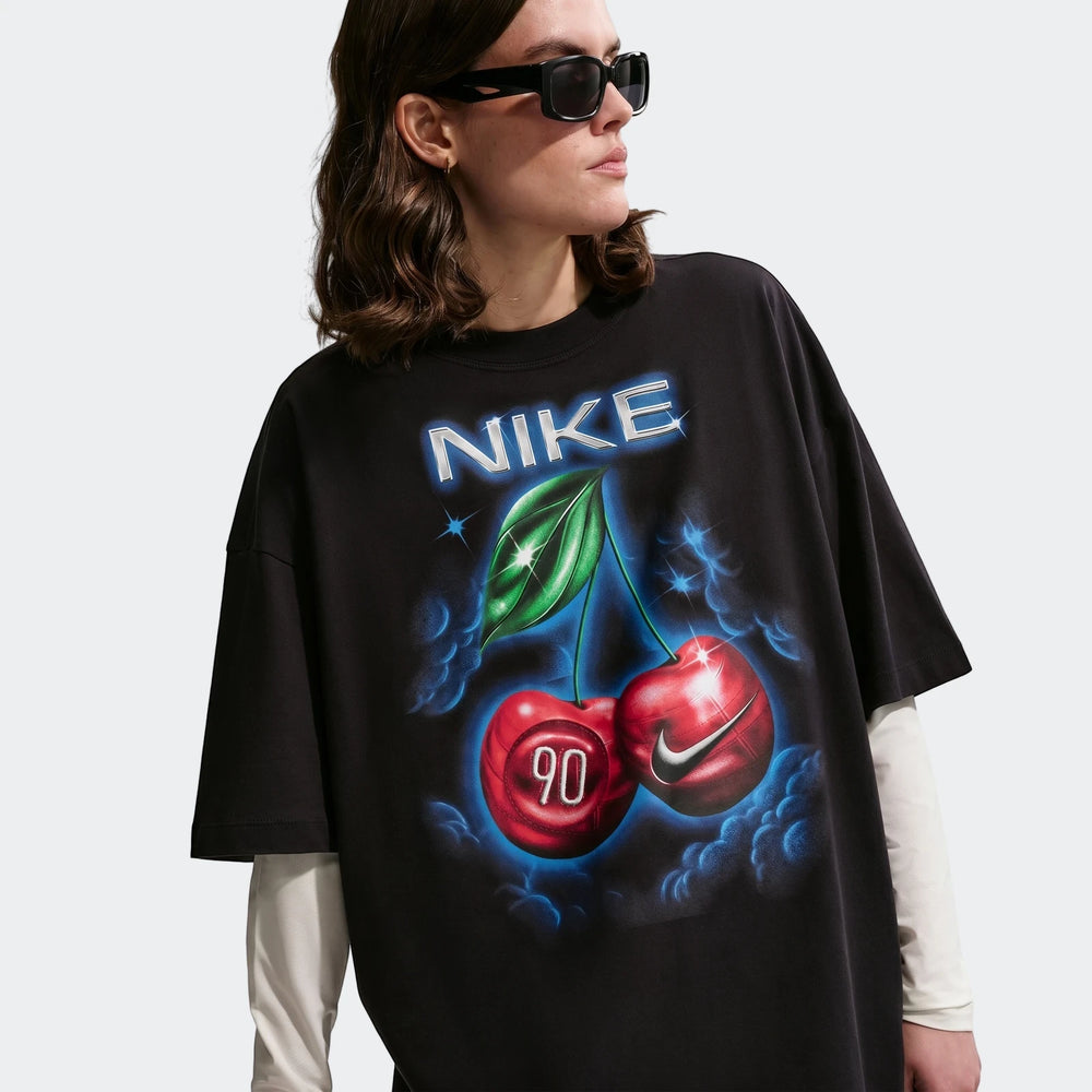 Nike Sportswear Classic black oversized t-shirt for women, featuring a vibrant cherry and Nike logo graphic, worn by a model.