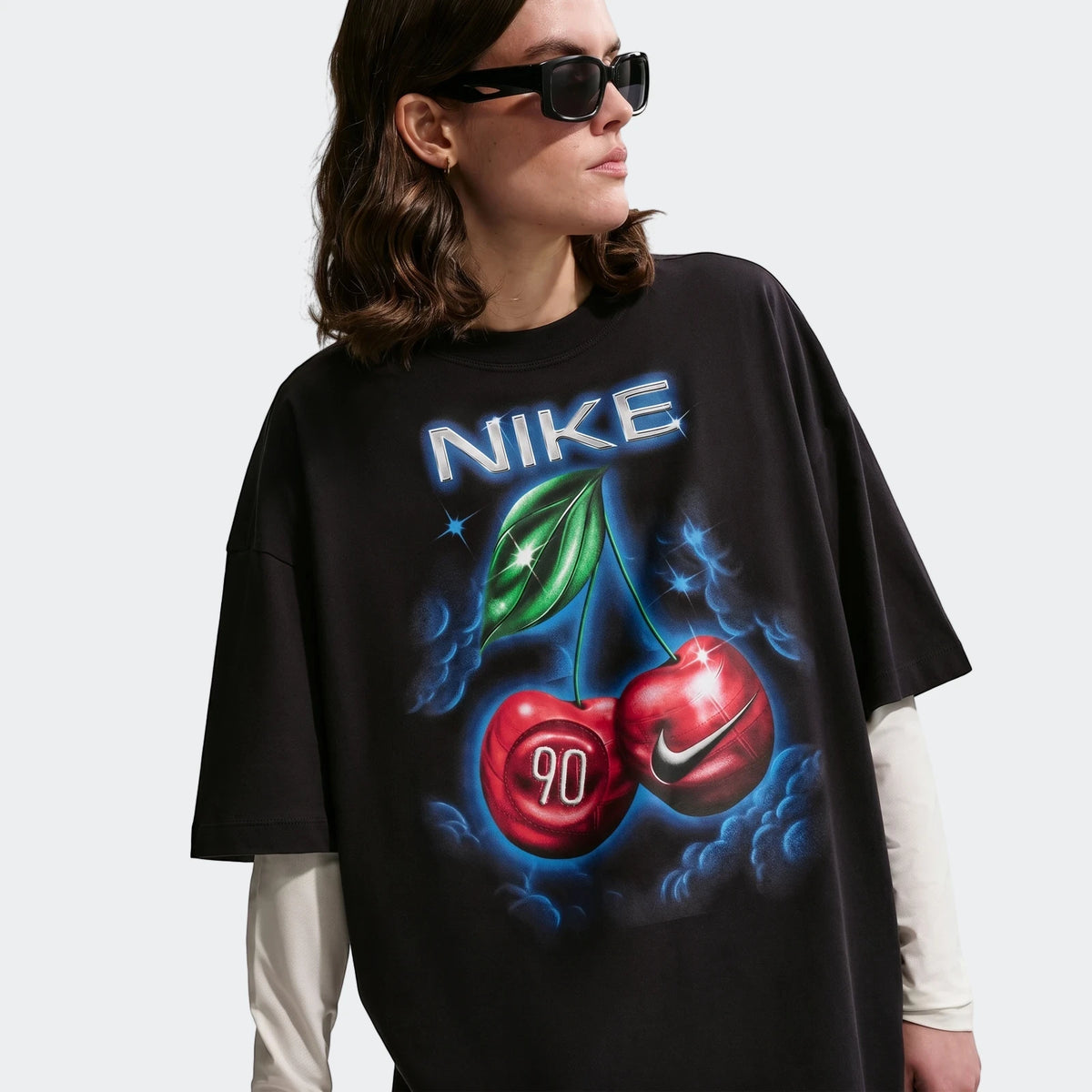 Nike Sportswear Classic black oversized t-shirt for women, featuring a vibrant cherry and Nike logo graphic, worn by a model.