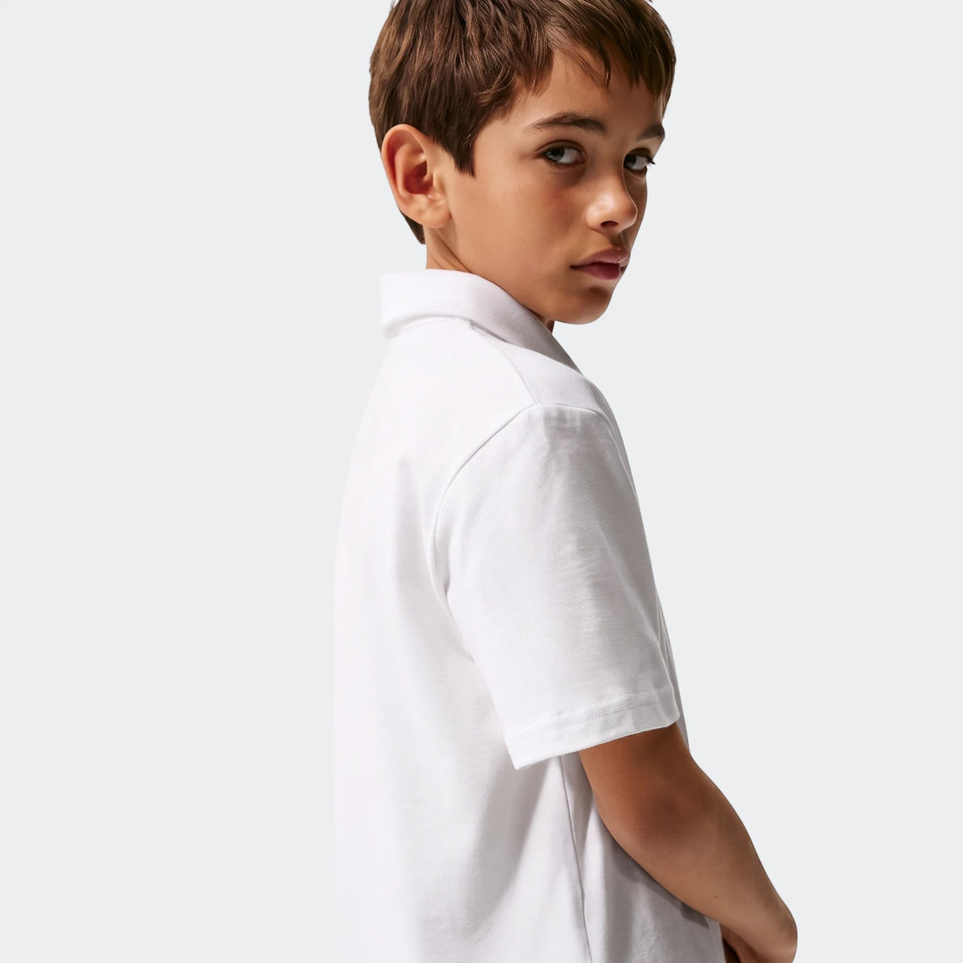 A young boy wearing a white Nike Sportswear Club Big Kids' Knit Short-Sleeve Polo, seen from the upper chest, looking back
