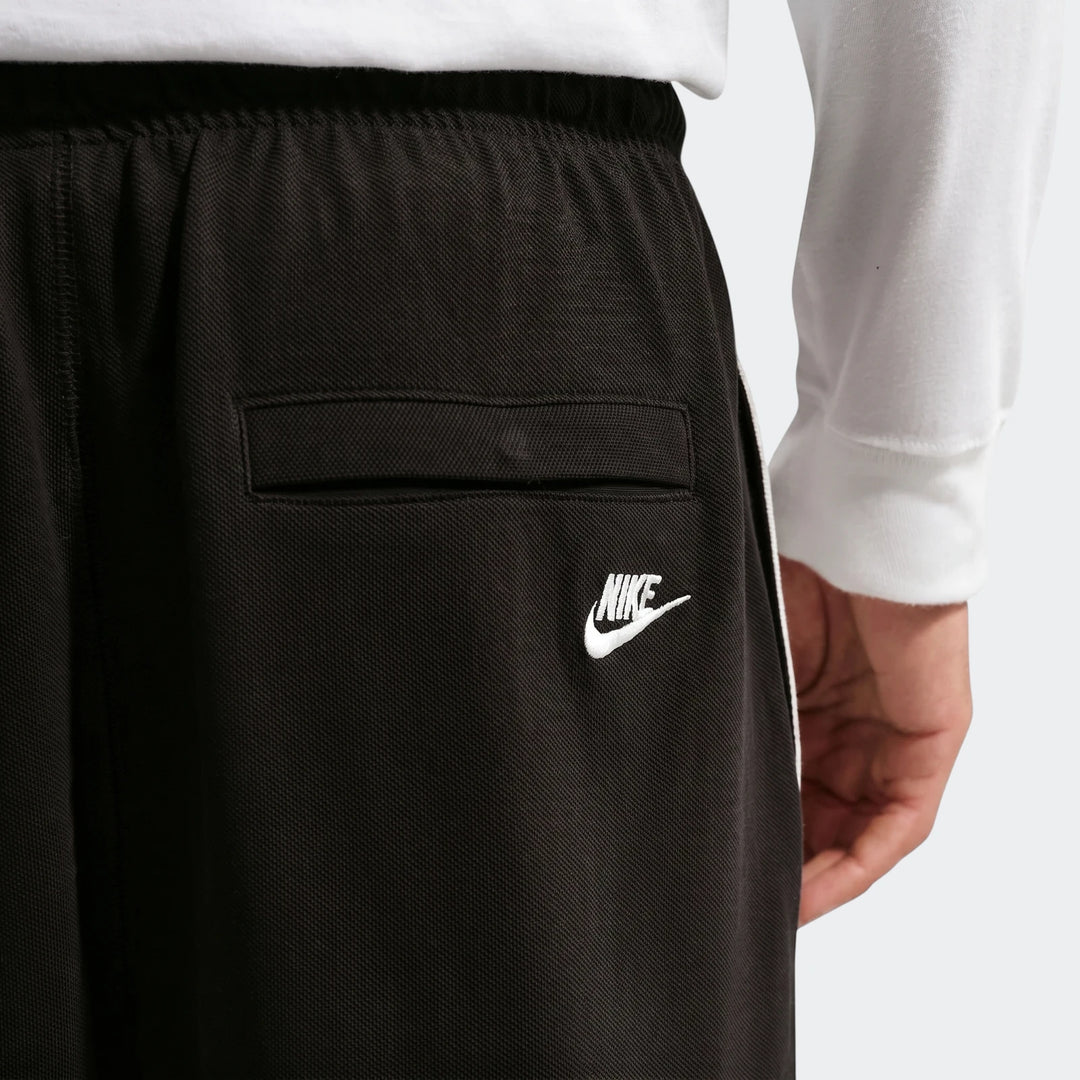 Close-up back view of Nike Sportswear Club black men's knit flow shorts with white side stripe and logo.