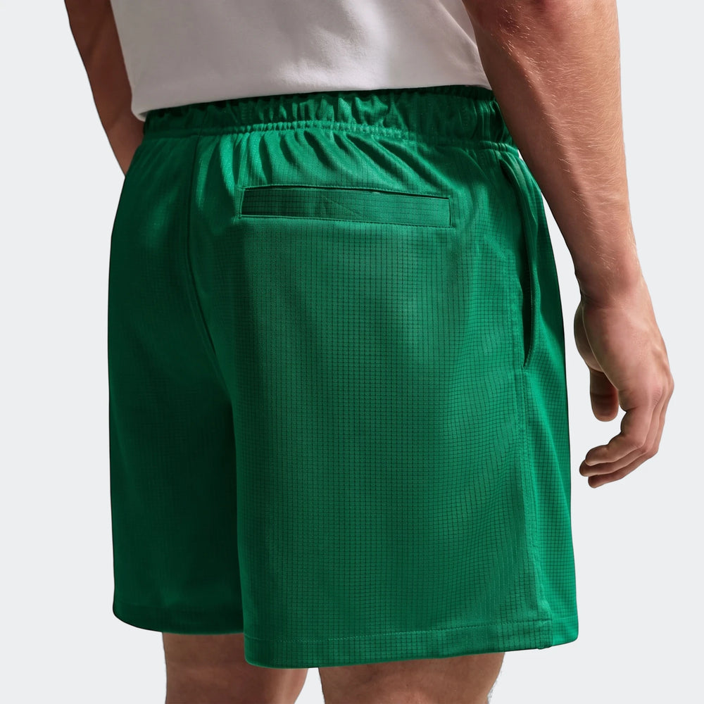 Back view of Nike Sportswear Club Green Men's Flow Shorts worn by a model, showing elastic waistband and back pocket detail.
