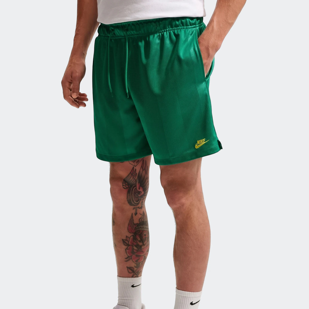 Nike Sportswear Club Green Men's Flow Shorts, featuring a drawcord waist and Nike logo, worn by a model.
