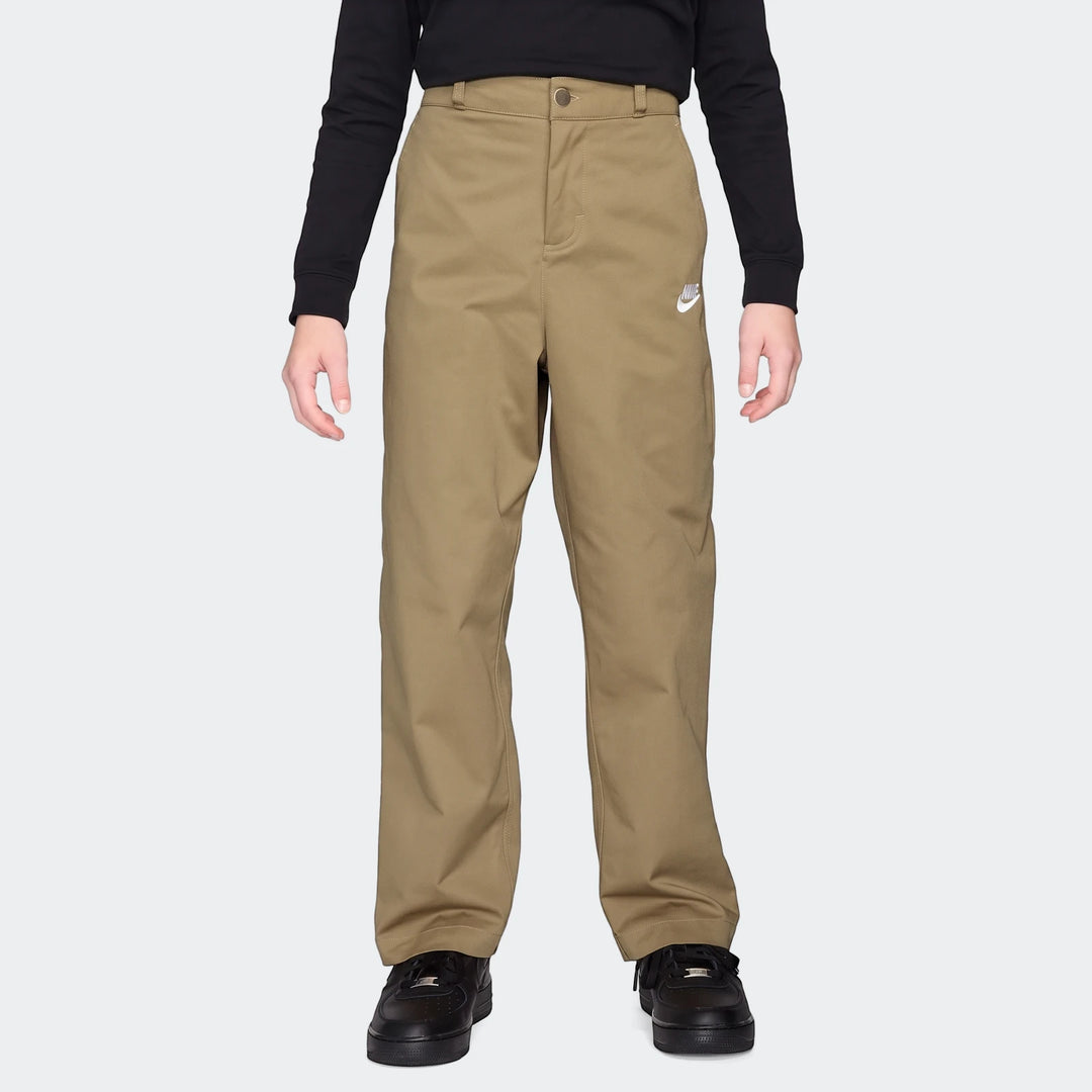 Nike Sportswear Club Big Kids' Woven Everyday Pants in khaki with a white Nike logo, worn by a child with a black