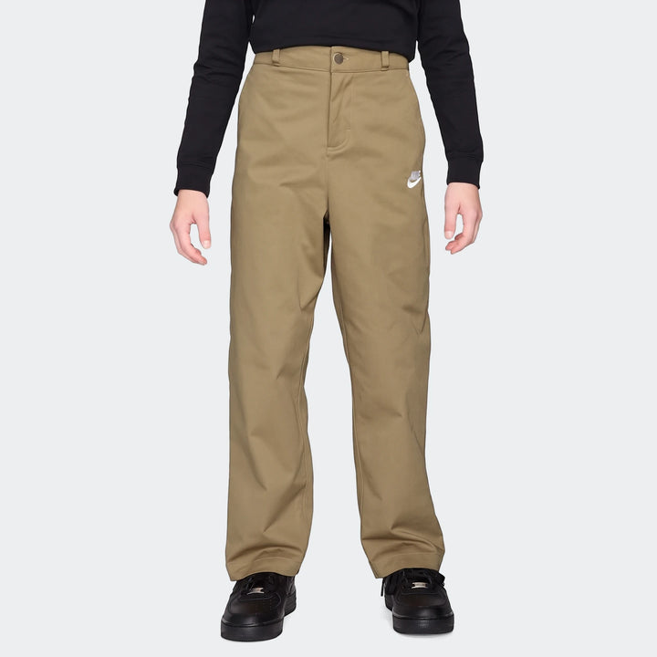 Nike Sportswear Club Big Kids' Woven Everyday Pants in khaki with a white Nike logo, worn by a child with a black