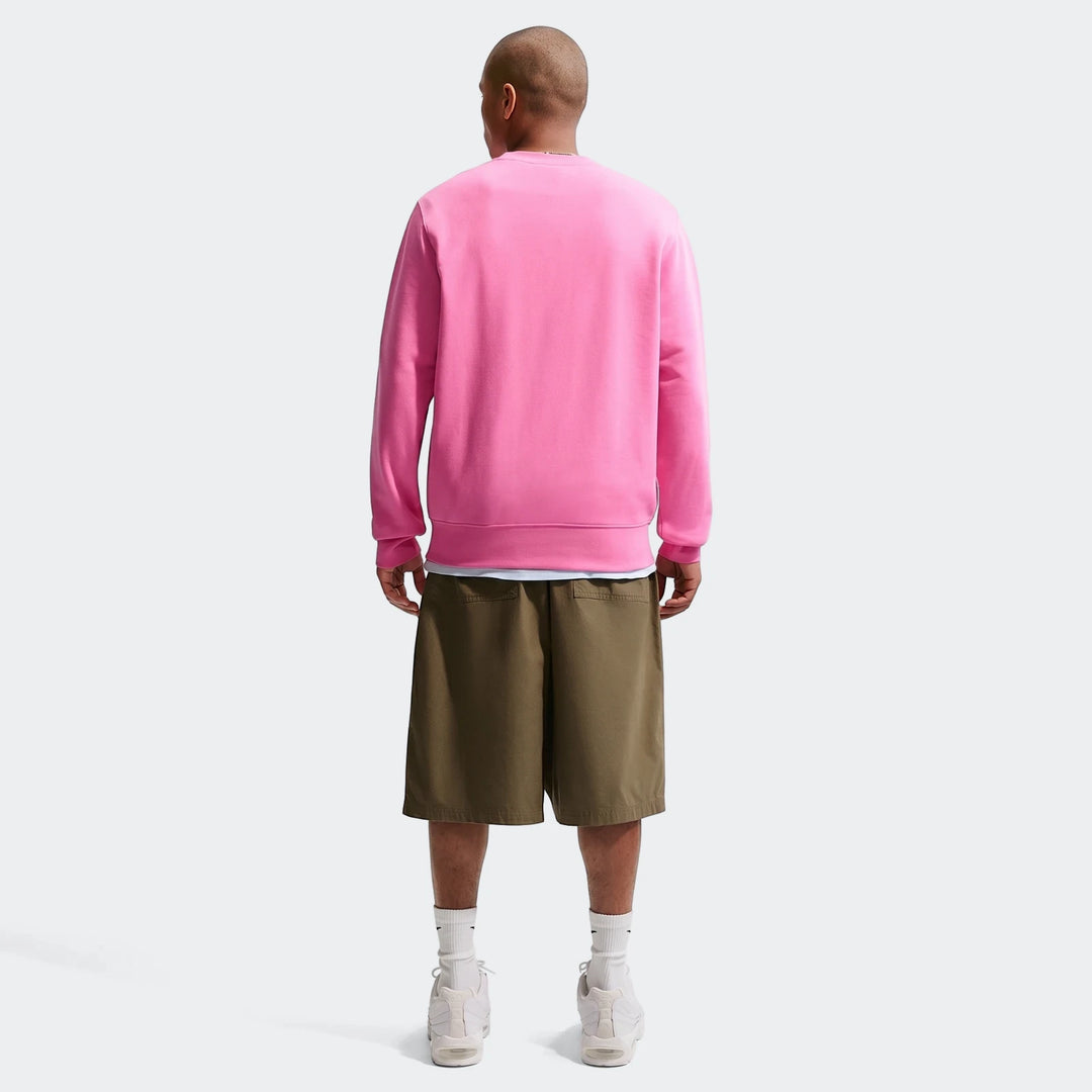 Men's Nike Sportswear Club French Terry crew-neck sweatshirt in pink, worn from the back with olive shorts and white