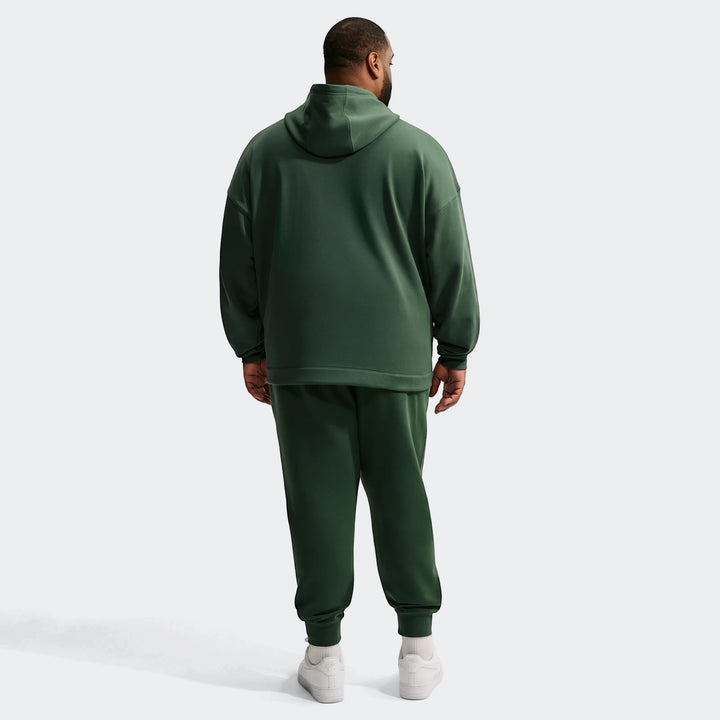 Dark green Nike Sportswear Club men's joggers and matching hoodie worn by a man, full body view from the back.