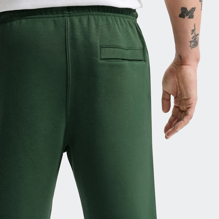 Back view of dark green Nike Sportswear Club Men's Joggers worn by a person, showing the elastic waist and back pocket.