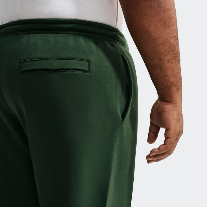 Dark green Nike Sportswear Club men's joggers, showing a close-up of the back pocket and side pocket opening on a model.